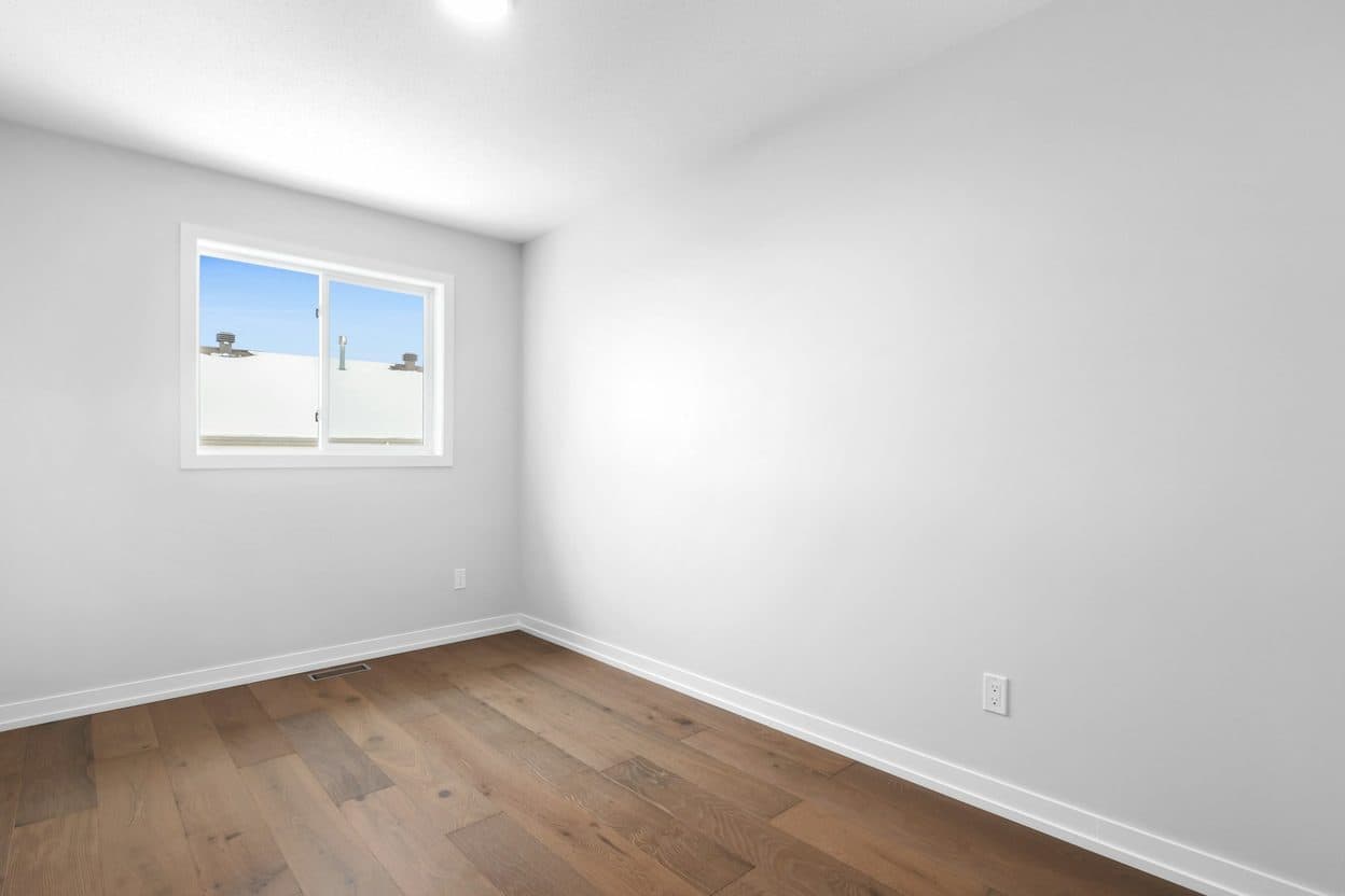 An empty bedroom with a window and wood floor, as uploaded